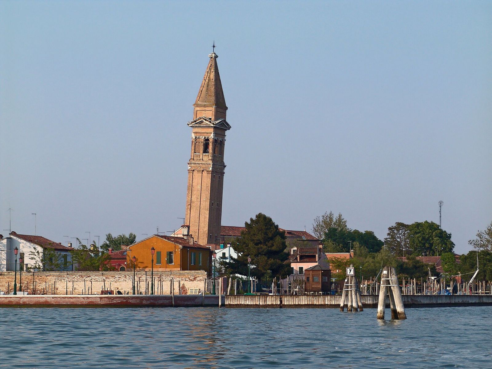 The leaning bell tower of San Martino rising above the rooftops of Burano, seen across the lagoon
