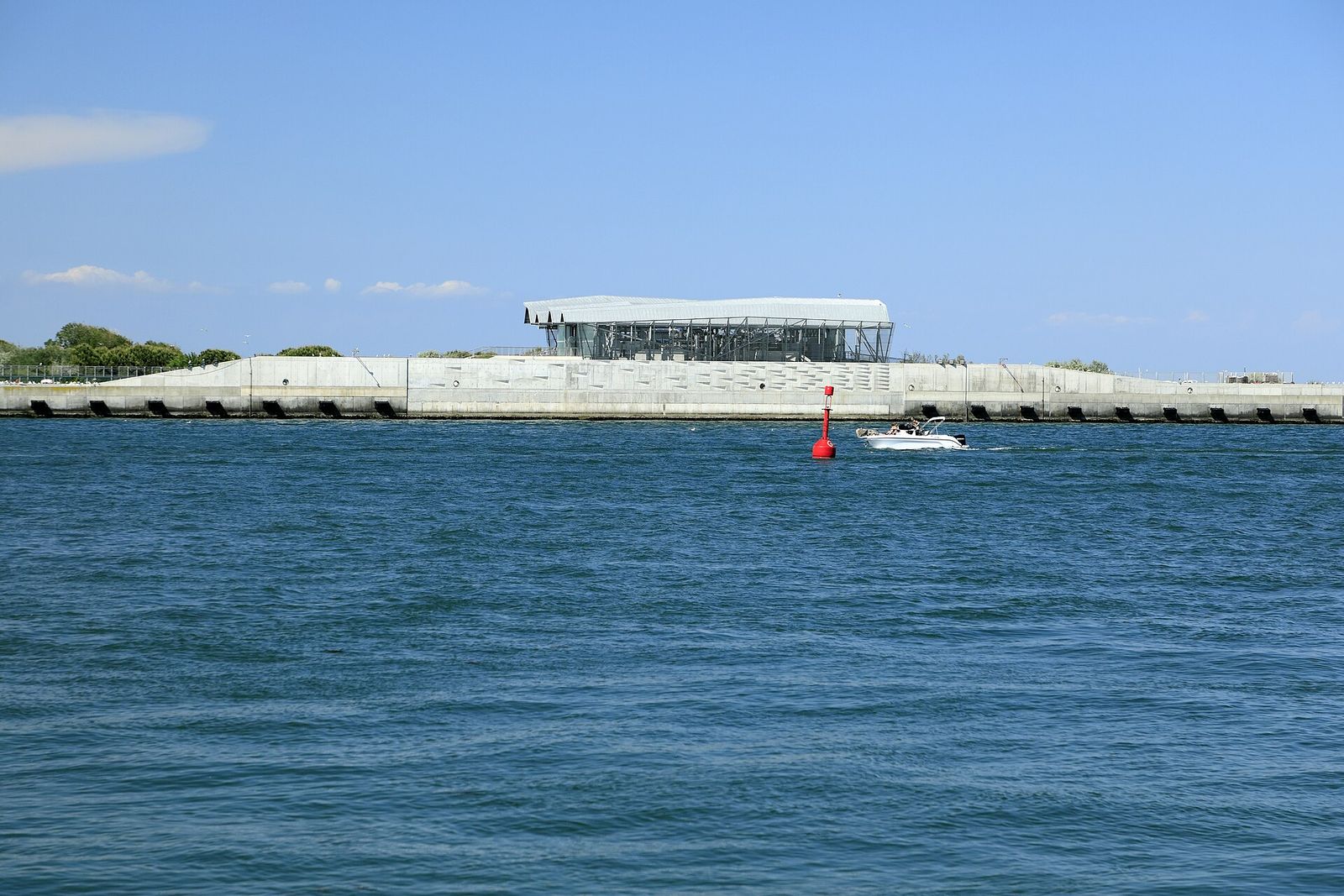 The MOSE flood-barrier installations at the Chioggia inlet: a long concrete embankment topped by a modern building, seen from the water