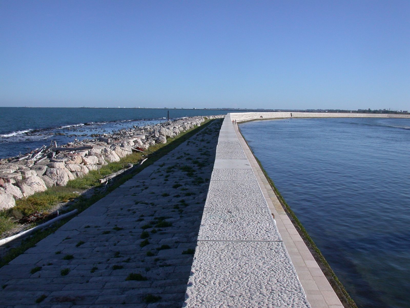 The Murazzi, the eighteenth-century stone sea wall at Pellestrina, with the Adriatic breaking against the rocks on the left and calm water on the right