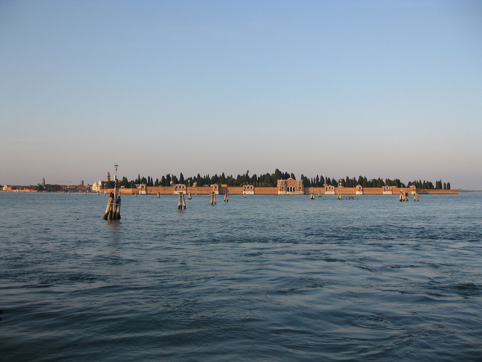 The cemetery island of San Michele seen across the lagoon, its long brick wall topped by dark cypresses in evening light